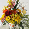 A colorful floral arrangement of seasonal flowers in a decorated ceramic container