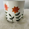 A colorful floral arrangement of seasonal flowers in a decorated ceramic container