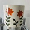 A colorful floral arrangement of seasonal flowers in a decorated ceramic container