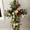 A standing cross, filled with a variety of seasonal flowers in whatever