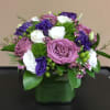 Beautiful modern cube vase with purple roses, purple lisianthus, white spray roses