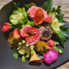 Hand tied medley of seasonal flowers presented in a black kraft paper