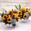 This fabulous fall arrangement features sunflowers, blue hydrangea and red roses. The