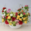 This arrangement mixes together roses, ranunculus, and anemones with seasonal greenery which