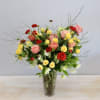 This arrangement is filled with vibrant red ranunculus, yellow spray roses, peach