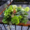Shades of green flowers and foliage in a round centerpiece for the