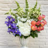 An elegant and vibrant arrangement of roses, hydrangeas, iris, and white stock.