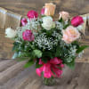 A dozen mixed roses arranged beautifully in a vase with greens and