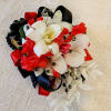 The red, white, and black wrist corsage is a striking accessory for