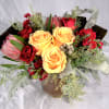 Amber-yellow roses complimented with darker hues of red protea flowers, magenta stocks