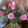 Dozen long stem lavender roses with filler designed in a glass vase.