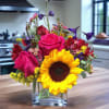 Popular clear cube vase full of vibrant sunflowers, roses, alstroemerias, delphinium &amp;
