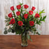 Beautifully designed 6 red roses with greens in a vase.  
