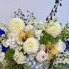 A unique flower arrangement featuring white and blue flowers with accents of