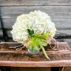 Hand gathered hydrangeas clustered together and placed in a cylinder vase accented