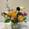 A stylish floral arrangement featuring soft pastel blooms with a bold pop