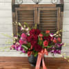 Red and purple tropical and traditional flowers in black ceramic pot.