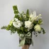 Seasonal green and white flowers arranged into a vase with a ribbon.