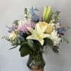 Seasonal white and pastel flowers arranged with greens into a vase. 