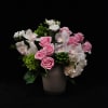 Beautiful pink roses and white orchids arranged atop a bed of green