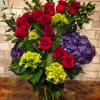 A gorgeous dozen red roses cascading down a bed of regal purple