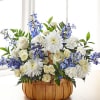 This basket arrangement has blue and white flowers such as delphinium, spray