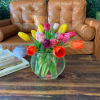 A wild assortment of different tulip varieties in a clear glass vase.