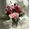 Roses, lilies, carnations and a hydrangea designed in a cracked glass vase.