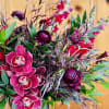 Unique and dramatic arrangement features richly colored maroon blooms! 