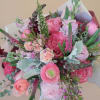 An assortment of pink hued flowers wrapped in premium paper.  (Bouquet