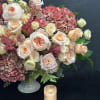 This stunning arrangement showcases peach garden roses, lush hydrangeas, and delicate spray