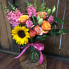 A mix of roses, snap dragons, sunflowers, and lisianthus placed into a