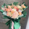 The bouquet features  a soft, romantic color palette, wrapped in rich