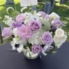 Low vase arrangement of white hydrangeas and soft lavender roses.