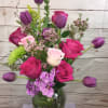 A joyful blend of purple tulips,hot pink roses,cream roses,a lavender orchid in