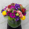 A delightful mix of seasonal flowers arranged in a fishbowl vase to