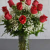 One Dozen Red Roses arranged in a clear glass vase with greenery