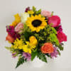A white Whicker arrangement designed with several roses, gerberas or sunflowers and