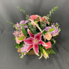 Lilies, roses, stock and more are arranged in a white washed basket.