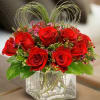 a dozen red roses in a glass cube accented with a fresh