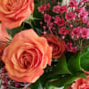 Vibrant orange spray roses, with cranberry colored waxflower, coral carnations and just
