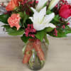 Vibrant orange spray roses, with cranberry colored waxflower, coral carnations and just
