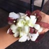 White orchid corsage with burgundy ribbon and rhinestone accents