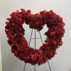 Mixture of red flowers in a heart shaped wreath