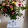 A mixture of seasonal spring flowers in an elegant pedestal vase.