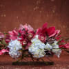 A stunning blend of vibrant crimson orchids and lush hydrangeas creates a