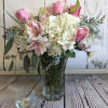 Fresh and white hydrangeas are accented with pink blossoms in a clear