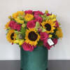 A luxury arrangement of hot pink roses, sunflowers, tulips and orchids flourish