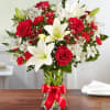 All-around arrangement with red roses and mini carnations; white Asiatic lilies and