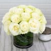 A dozen white roses in a modern styled shorter vase with greenery